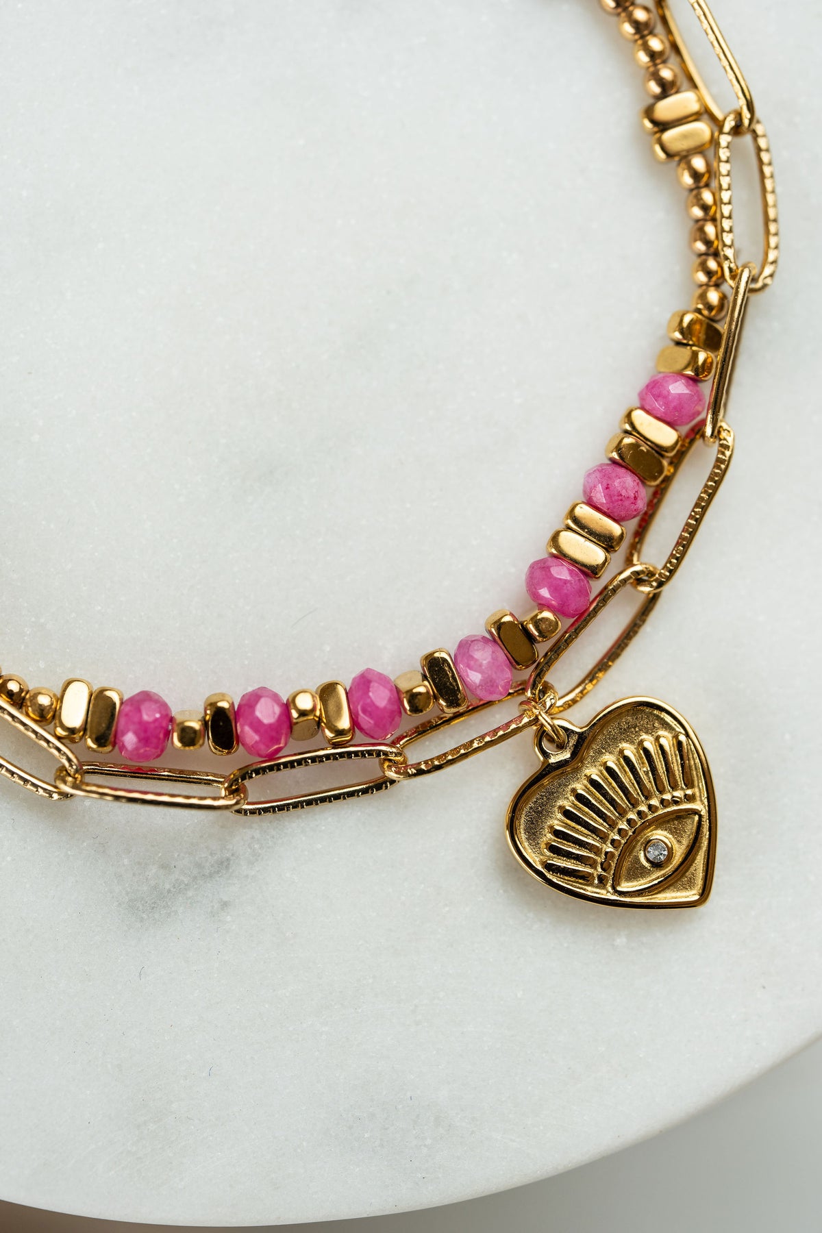 Pulsera doble de acero dorado y piedras en tonos rosa con dije corazón