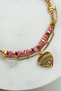 Pulsera doble de acero dorado y piedras en tonos rosa con dije corazón