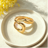 Anillo Praia dorado de acero quirúrgico con diseño abierto y forma curva orgánica.