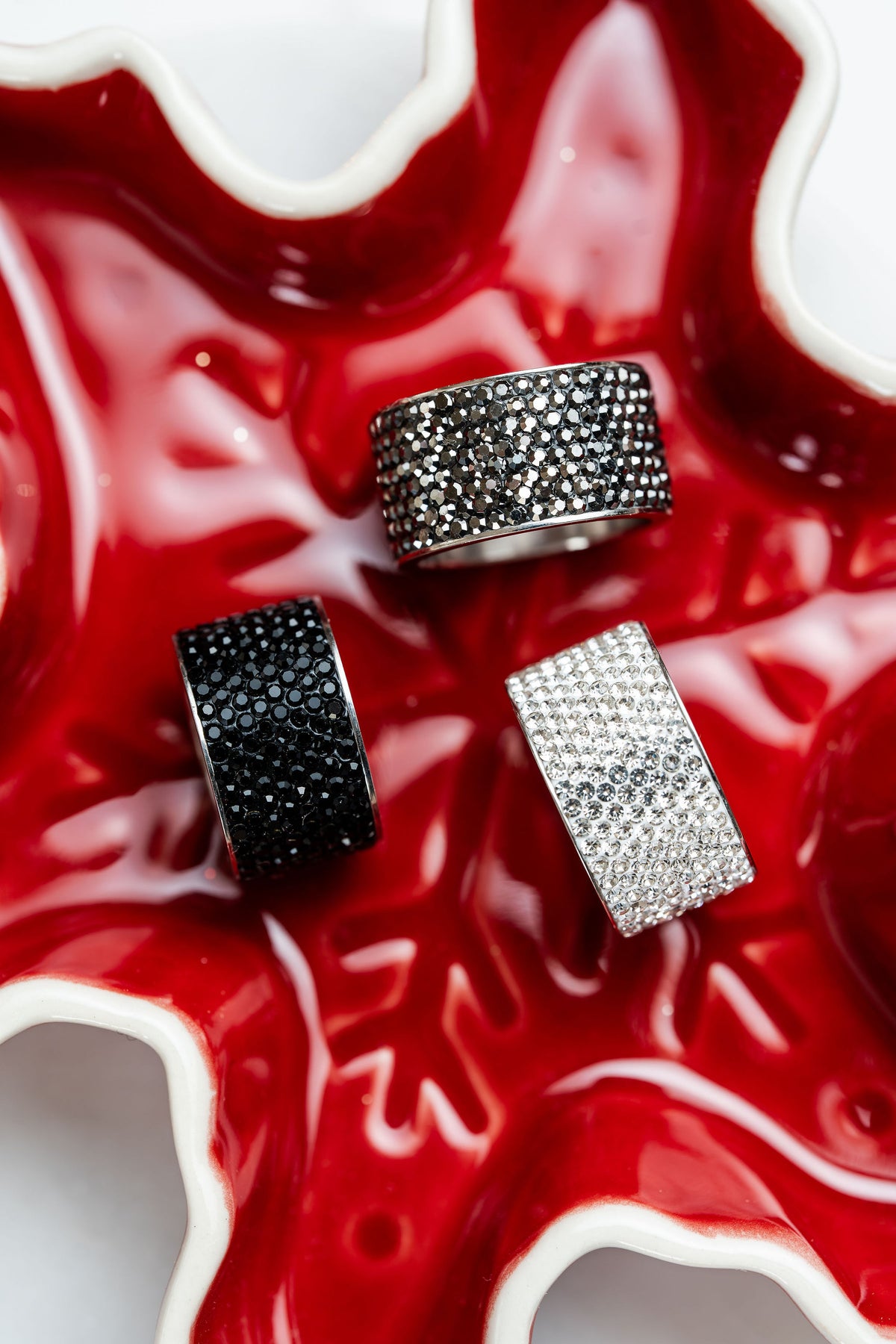 anillos anchos de acero plateado con cristales oscuros carlota en fondo rojo