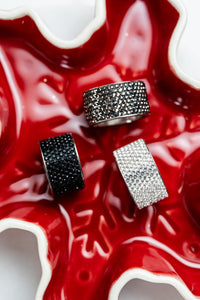 anillos anchos de acero plateado con cristales oscuros carlota en fondo rojo