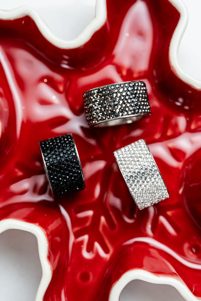 anillos anchos de acero plateado con cristales oscuros carlota en fondo rojo