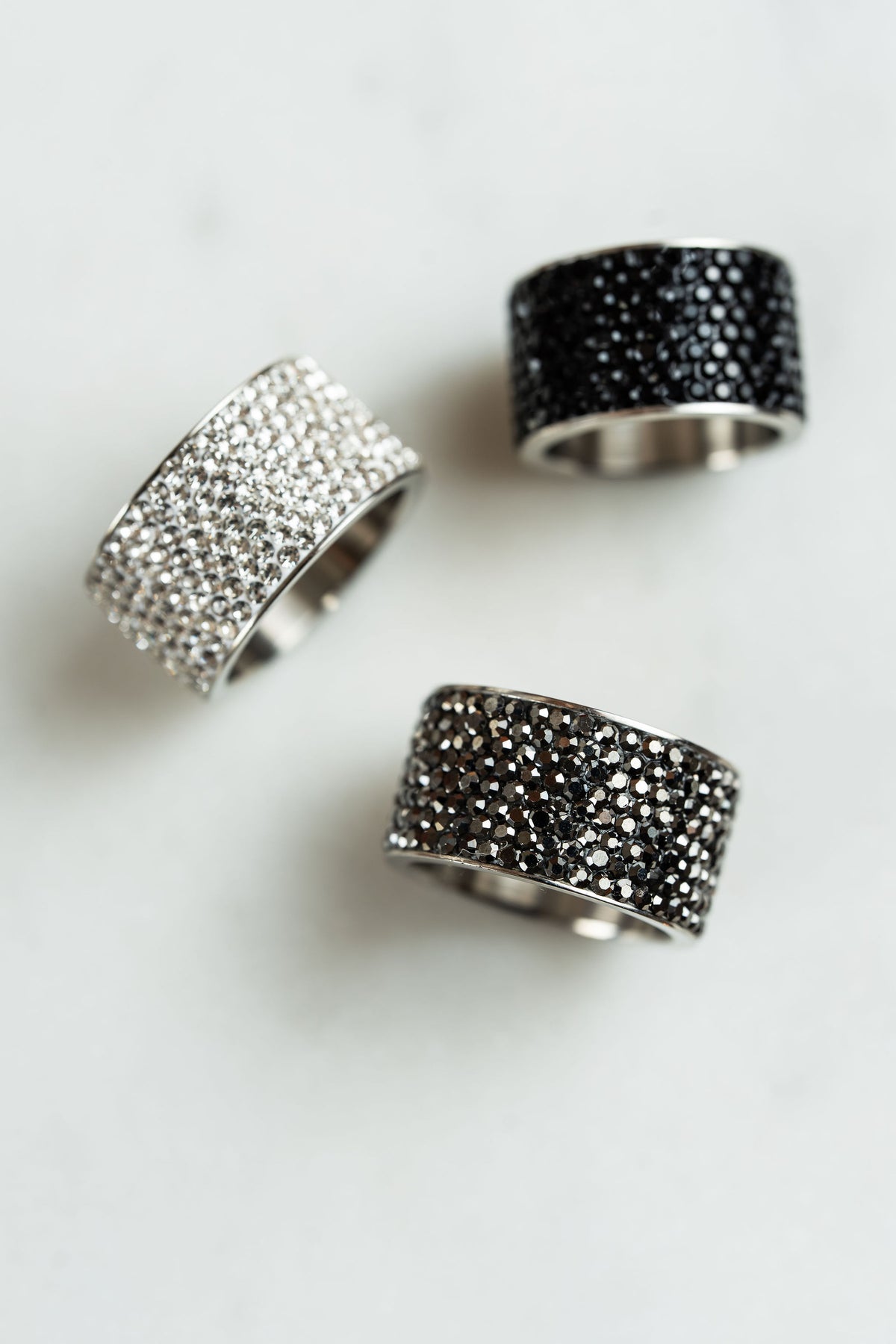 Anillos de acero y brillos anchos en fono blanco, colección de CARLOTA