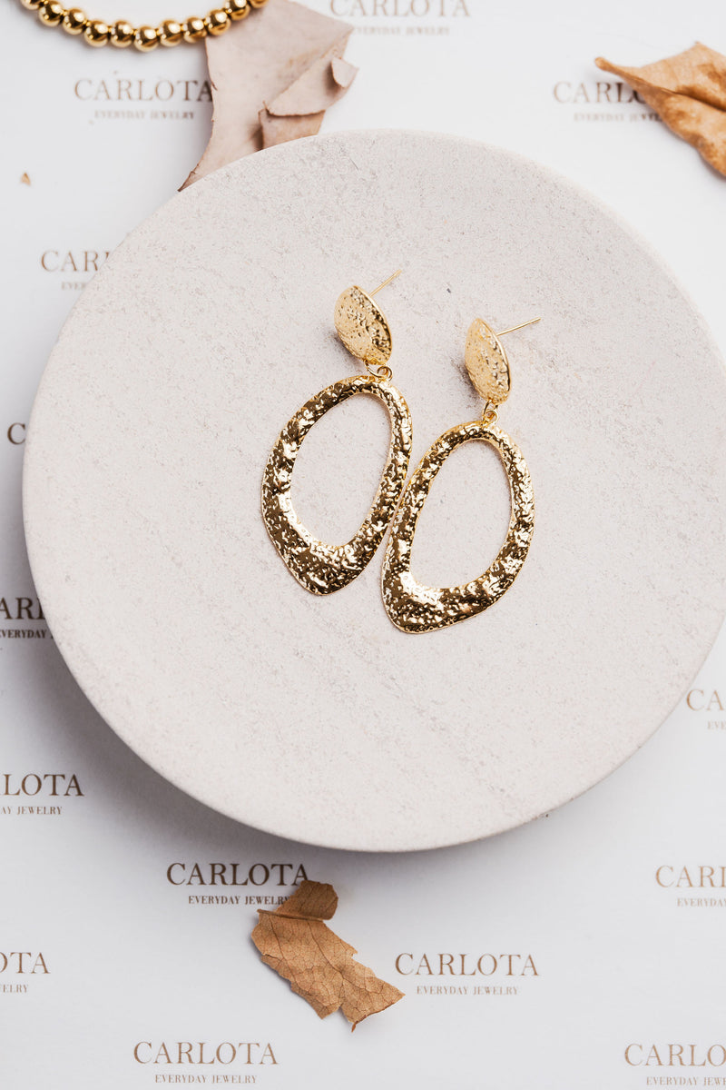 Aros colgantes dorados con textura martillada y forma ovalada irregular, modelo Edna de CARLOTA.