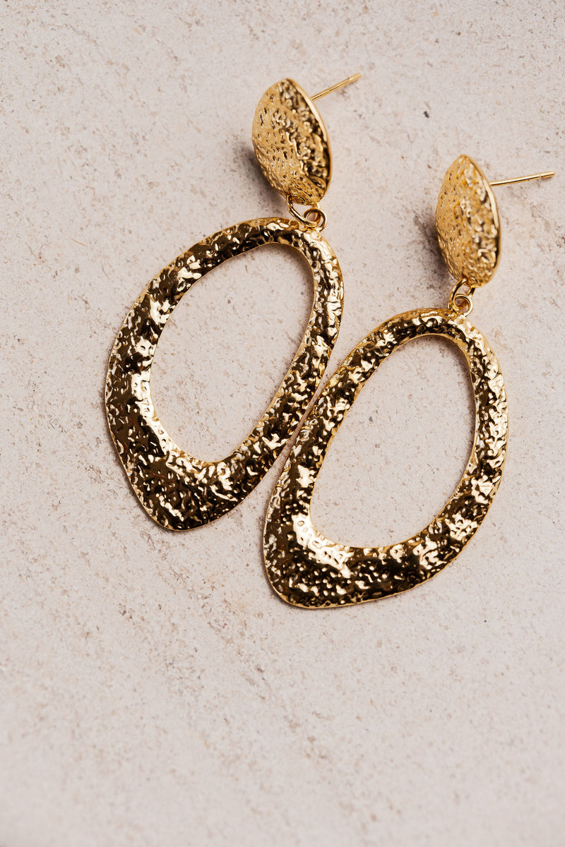 Aros colgantes dorados con textura martillada y forma ovalada irregular, modelo Edna de CARLOTA.
