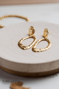 Aros colgantes dorados con textura martillada y forma ovalada irregular, modelo Edna de CARLOTA.