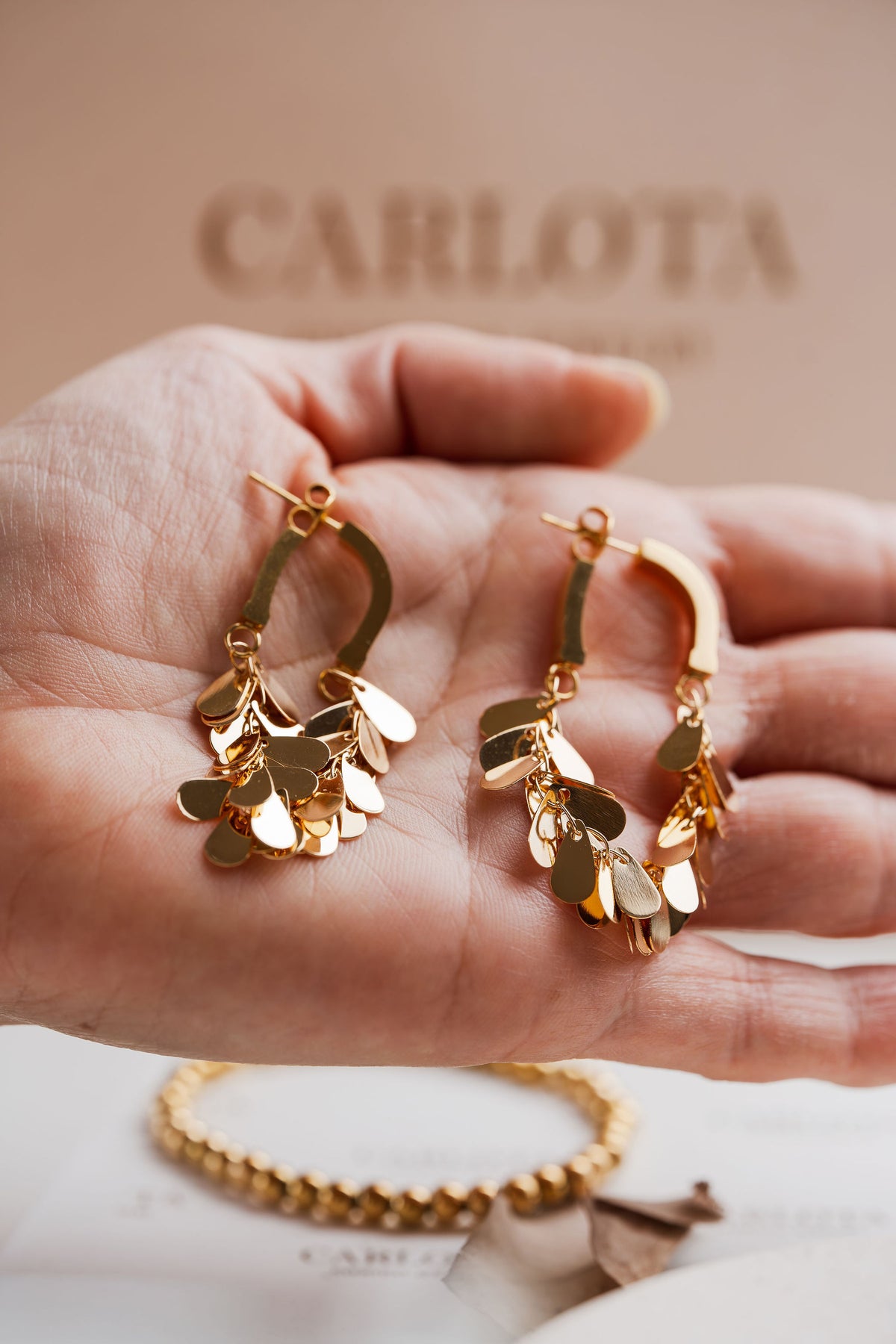 Pendientes con movimiento en acero y baño de oro de CARLOTA en mano
