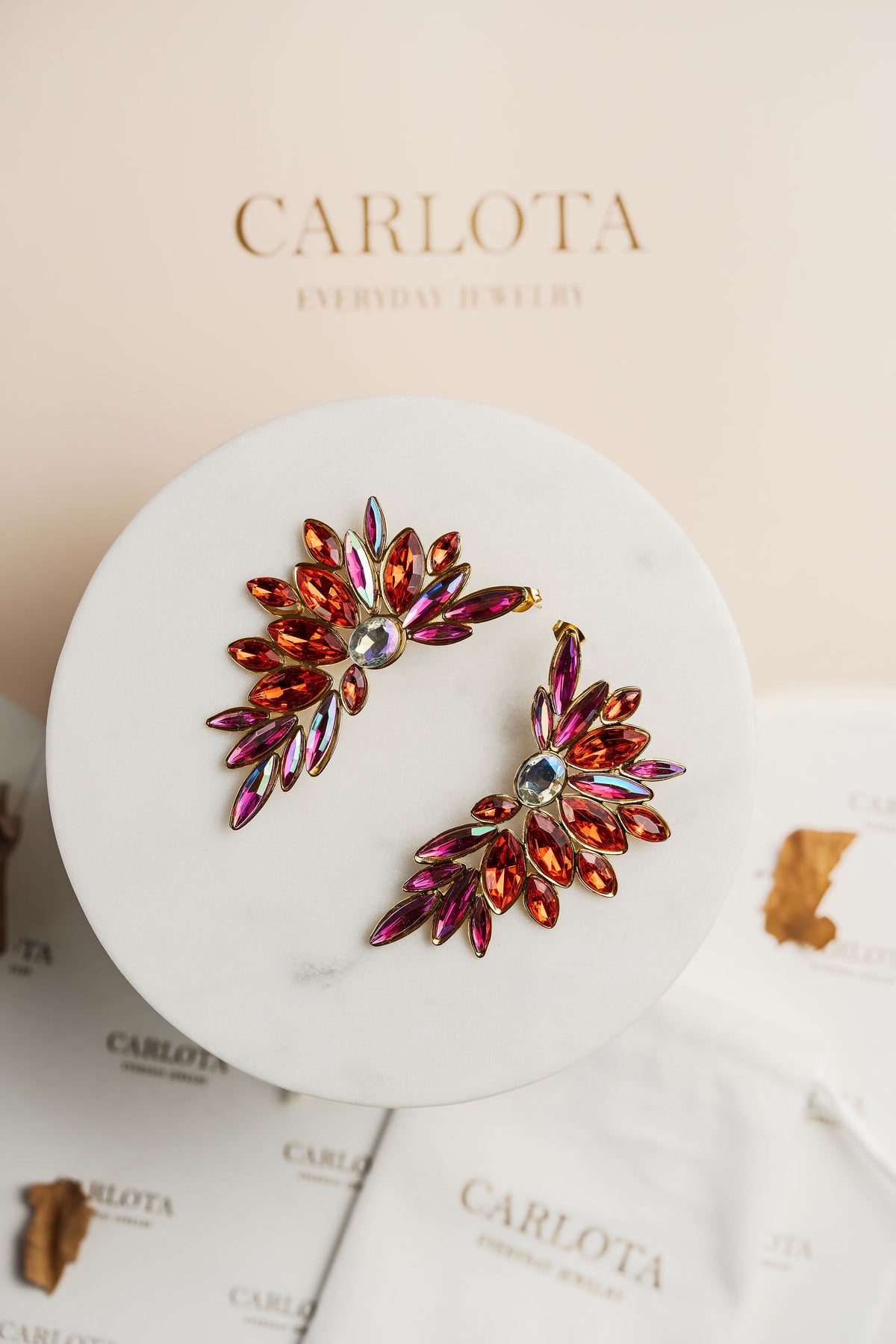 Aros en tonos rojos abiertos con forma geométrica irregular y acabado brillante, modelo Larisa de CARLOTA.