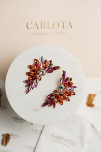 Aros en tonos rojos abiertos con forma geométrica irregular y acabado brillante, modelo Larisa de CARLOTA.