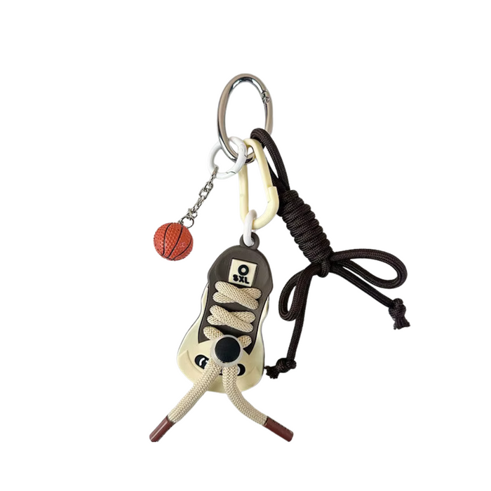 Llavero con pelota de básquet, zapato deportivo y cordón marrón, fotografiado sobre fondo claro. Ideal para llaves o como accesorio deportivo.