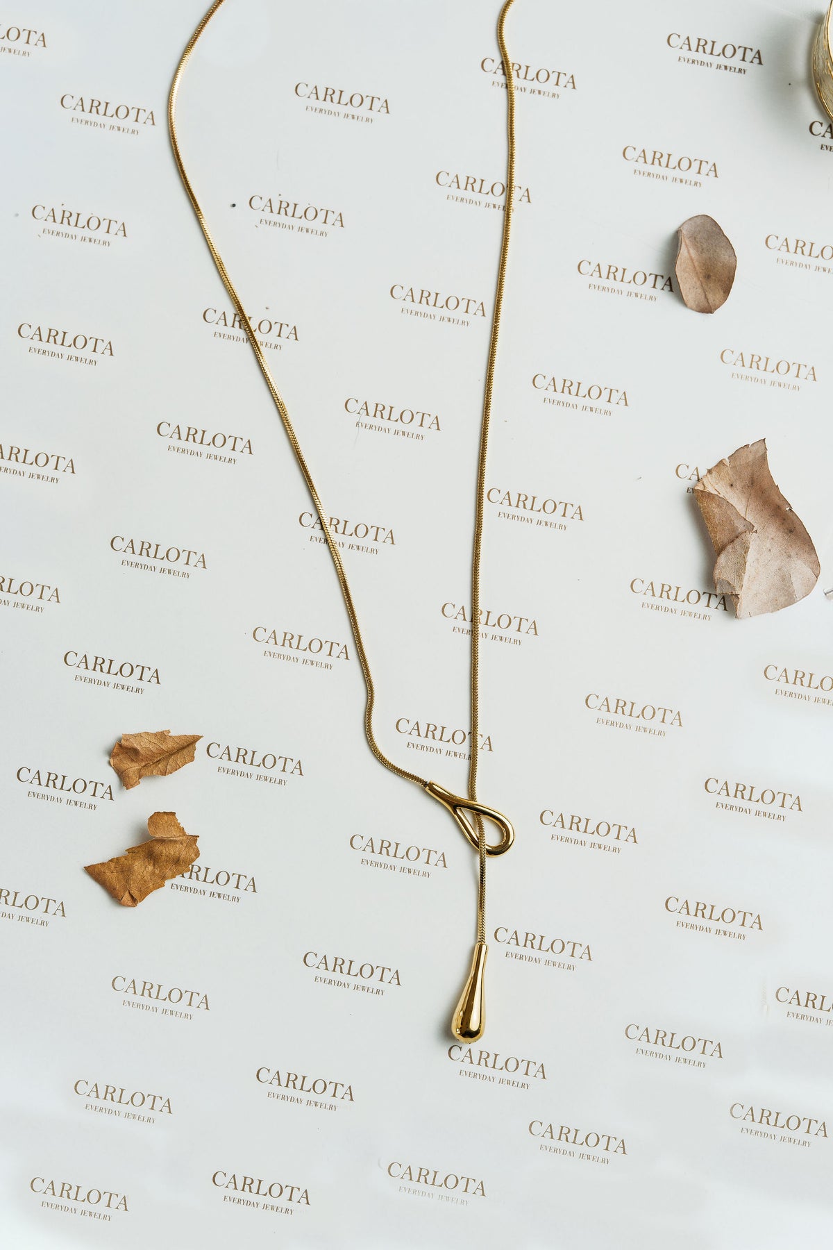 Collar dorado largo con forma de lazo irregular y gota alargada, modelo Débora de CARLOTA.