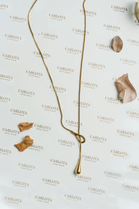 Collar dorado largo con forma de lazo irregular y gota alargada, modelo Débora de CARLOTA.