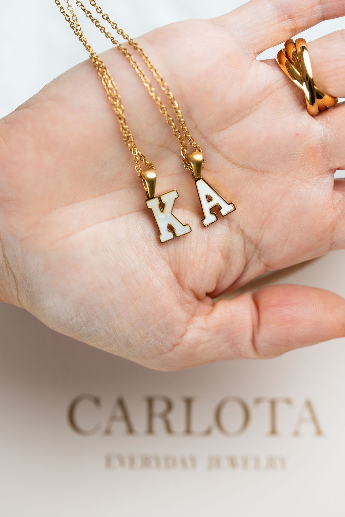 Collar de acero quirúrgico y baño de oro 18k con pendiente incial en mano