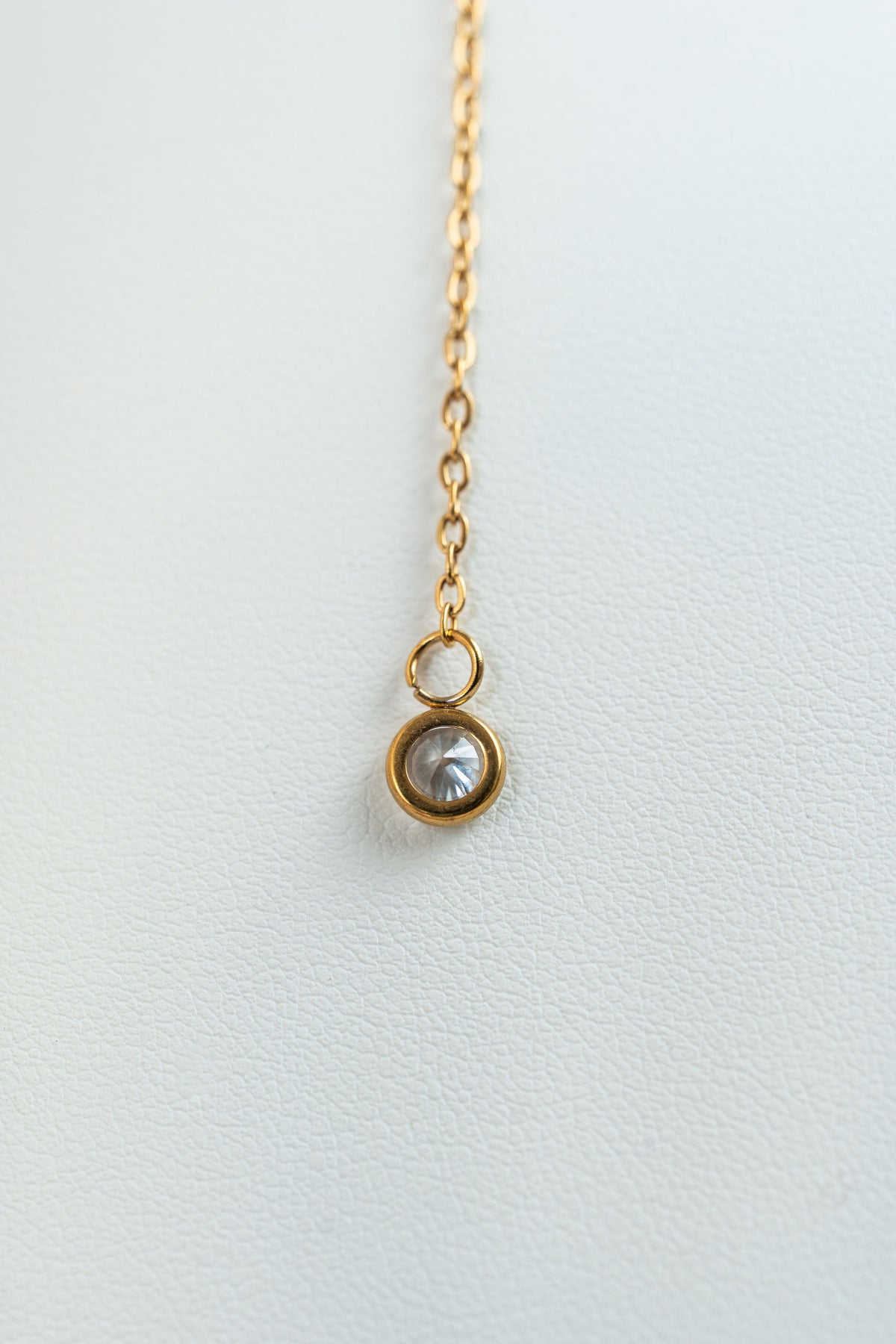 Collar dorado con detalle de piedra brillante en fondo blanco