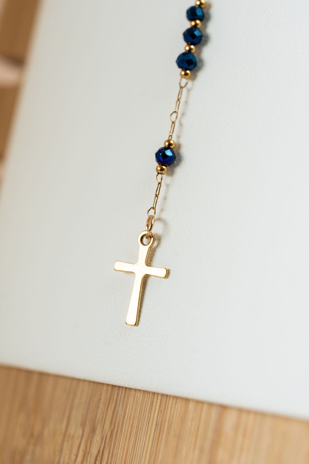 Detalle de Cruz en acero con baño de oro en collar rosario de CARLOTA