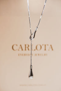 Collar largo de acero quirúrgico en tono plateado con diseño tipo lazo, modelo Débora sin baño de CARLOTA.