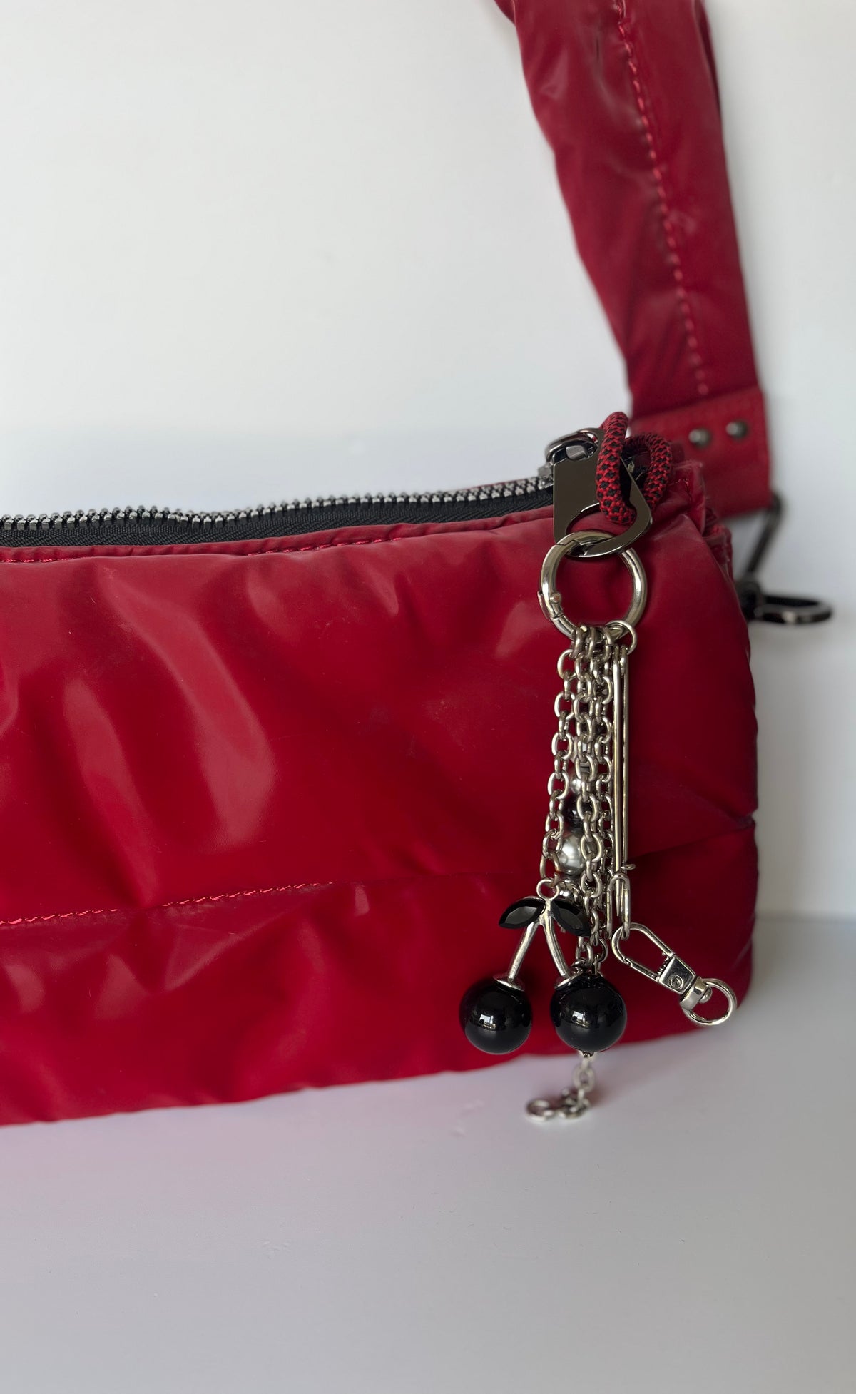 Llavero con cerezas negras brillantes y gancho metálico,  en cartera roja