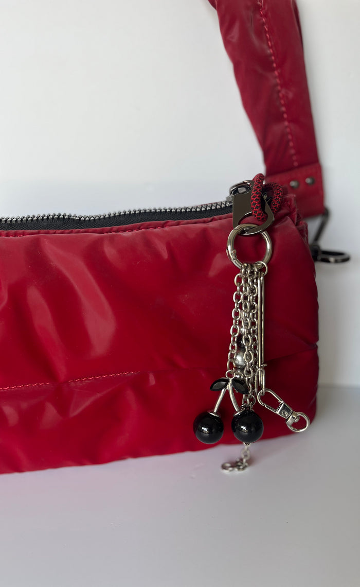 Llavero con cerezas negras brillantes y gancho metálico,  en cartera roja