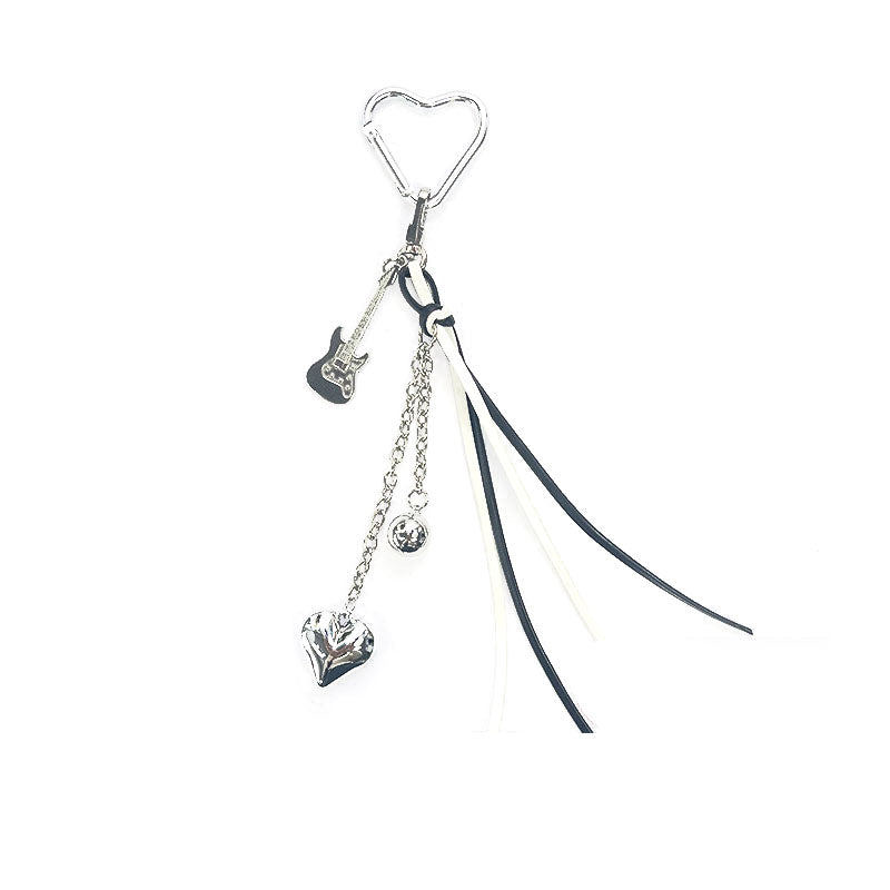 Llavero plateado con dije de guitarra eléctrica, corazón metálico, cadenas decorativas y cintas en blanco y negro – diseño moderno CARLOTA