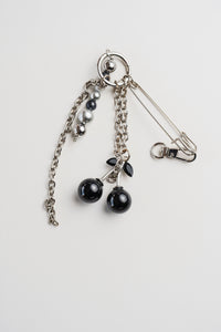 Llavero con cerezas negras brillantes y gancho metálico, sobre fondo rosa claro. Accesorio decorativo con estilo pop y original.