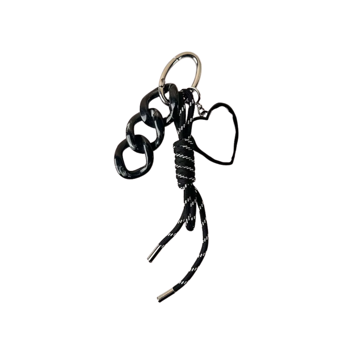 Llavero negro con cinta y dije de corazón, sobre fondo neutro. Ideal como accesorio para llaves, mochila o cartera.