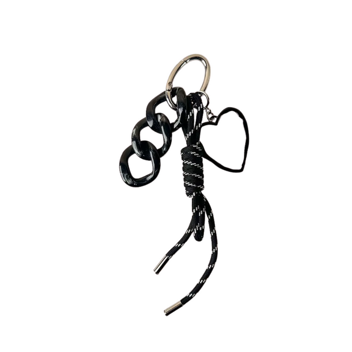 Llavero negro con cinta y dije de corazón, sobre fondo neutro. Ideal como accesorio para llaves, mochila o cartera.