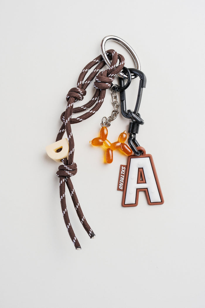 Llavero con perro naranja, letra A y cordón marrón en fondo blanco.Ideal para carteras.