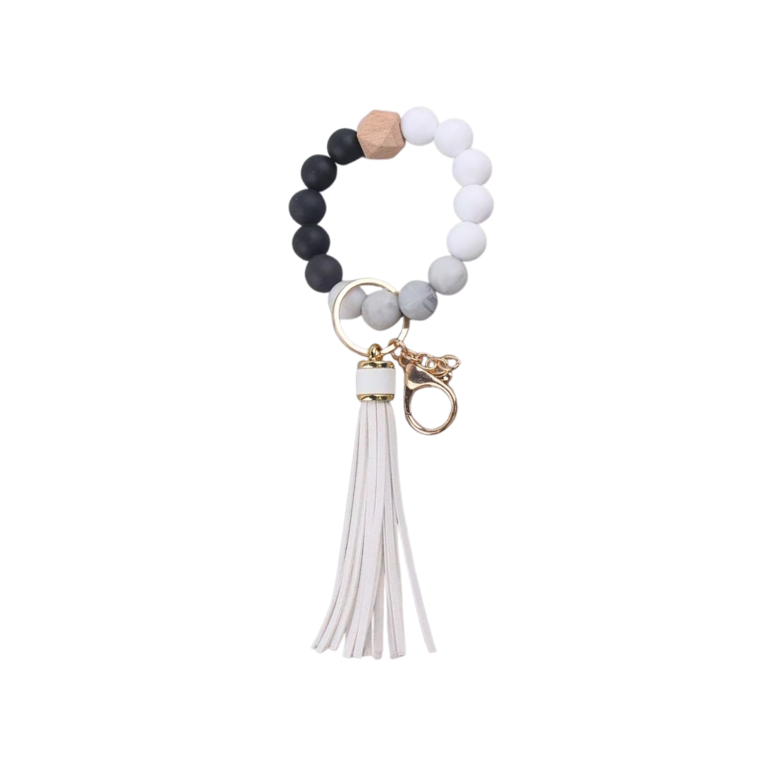 Llavero pulsera elástica con cuentas de silicona blancas y negras y flecos en simil cuero blancos, ideal para usar en la muñeca o colgar en cartera.