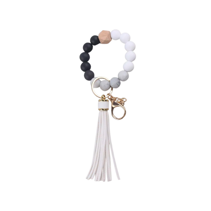 Llavero pulsera elástica con cuentas de silicona blancas y negras y flecos en simil cuero blancos, ideal para usar en la muñeca o colgar en cartera.