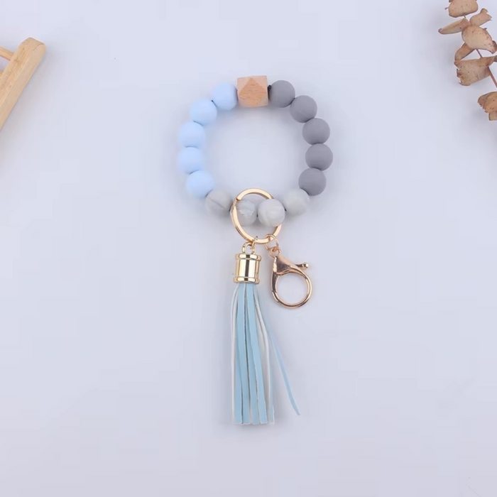 Llavero pulsera en tonos celestes y grises con fleco y cuentas de silicona