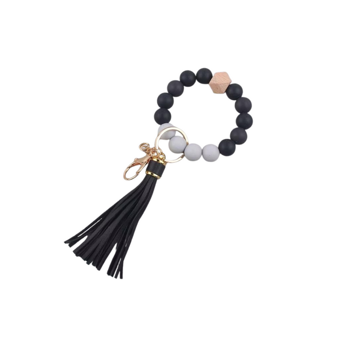 Llavero pulsera negra con cuentas de silicona, dije de madera y flecos de cuero sintético.