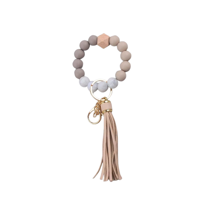 Llavero pulsera nude con cuentas de silicona y flecos, ideal para usar en la muñeca o colgar en cartera.
