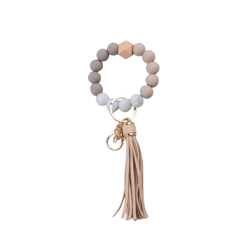 Llavero pulsera nude con cuentas de silicona y flecos, ideal para usar en la muñeca o colgar en cartera.
