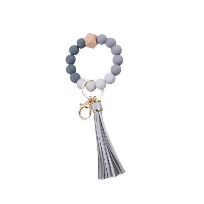 Llavero pulsera elástica con cuentas de silicona y flecos en tonos plateados, ideal para usar en la muñeca o colgar en cartera.