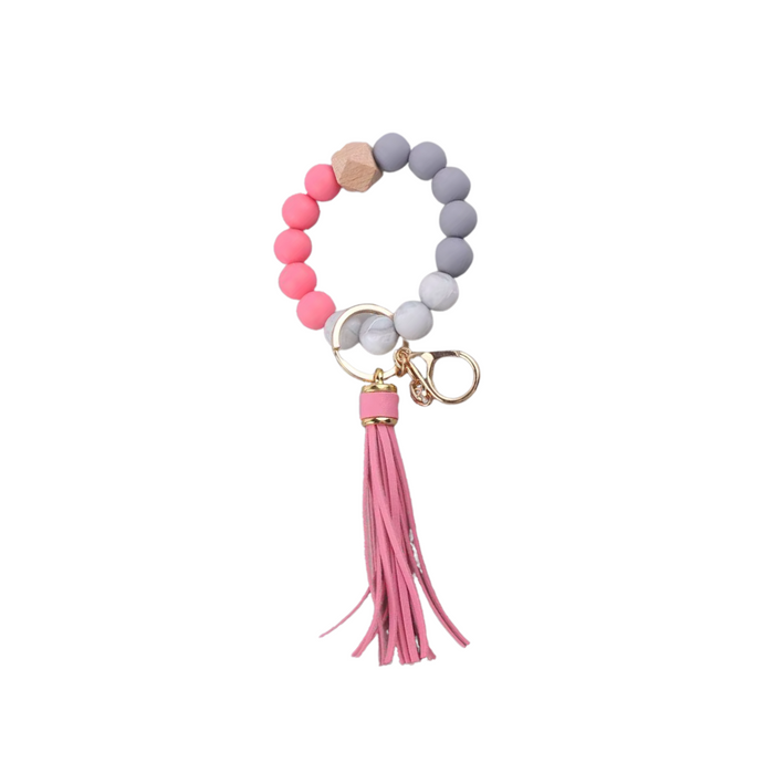 Llavero pulsera elástica con cuentas de silicona rosa y gris y flecos en simil cuero rosados, ideal para usar en la muñeca o colgar en cartera.