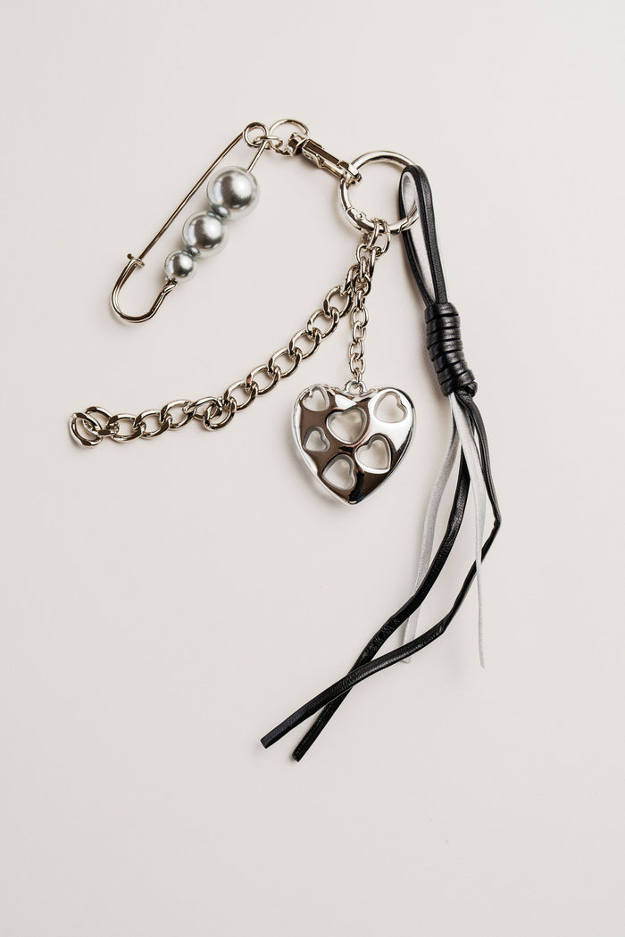 Llavero con dije de corazón en color plateado, cadenas decorativas y cintas negras y blancas, estilo urbano y moderno