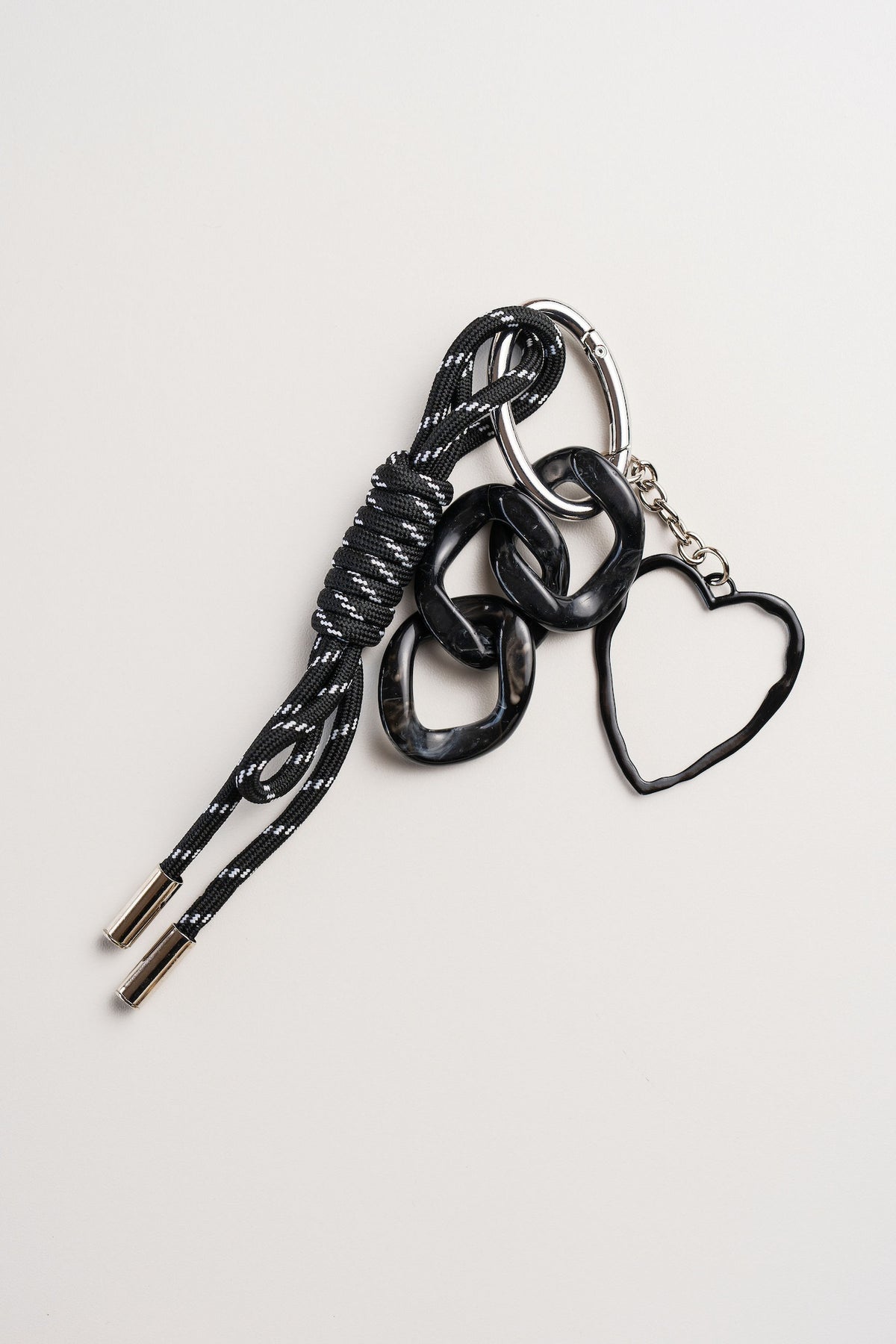 Llavero negro con cordón y dije de corazón, sobre fondo neutro. Ideal como accesorio para llaves, mochila o cartera.