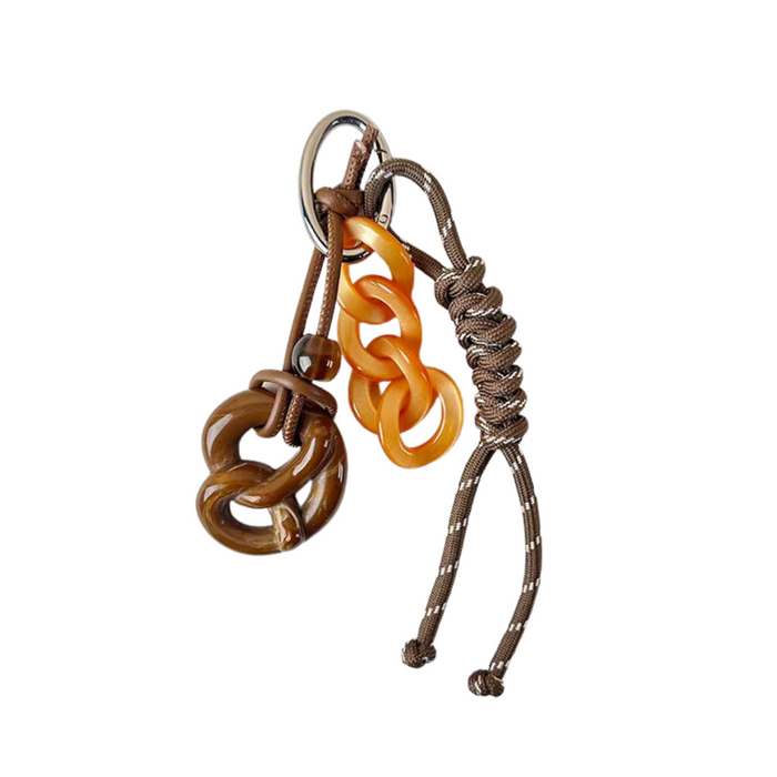 Llavero con cuerda marrón y detalles naranjas, sobre fondo neutro. Diseño rústico y elegante, ideal para llaves o bolso.