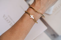 pulsera de cuenta y cruz con escalva de acero y oro en brazo