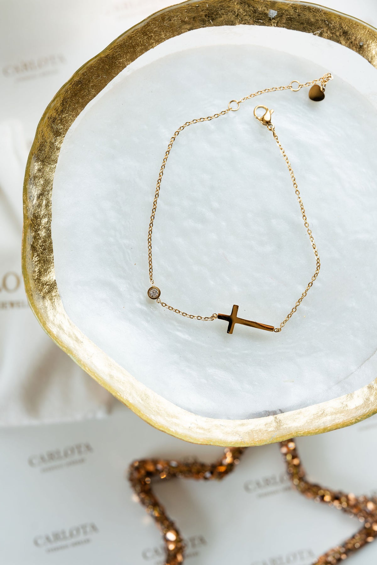 Tobillera dorada con cruz en acero quirúrgico y punto luz de CARLOTA