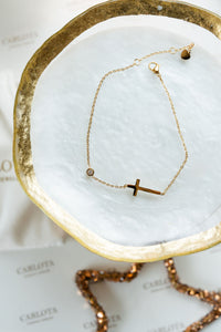 Tobillera dorada con cruz en acero quirúrgico y punto luz de CARLOTA