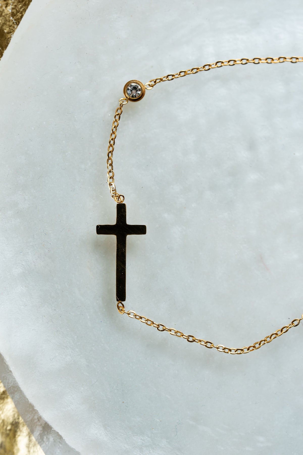 Tobillera dorada con cruz en acero quirúrgico y punto luz de CARLOTA