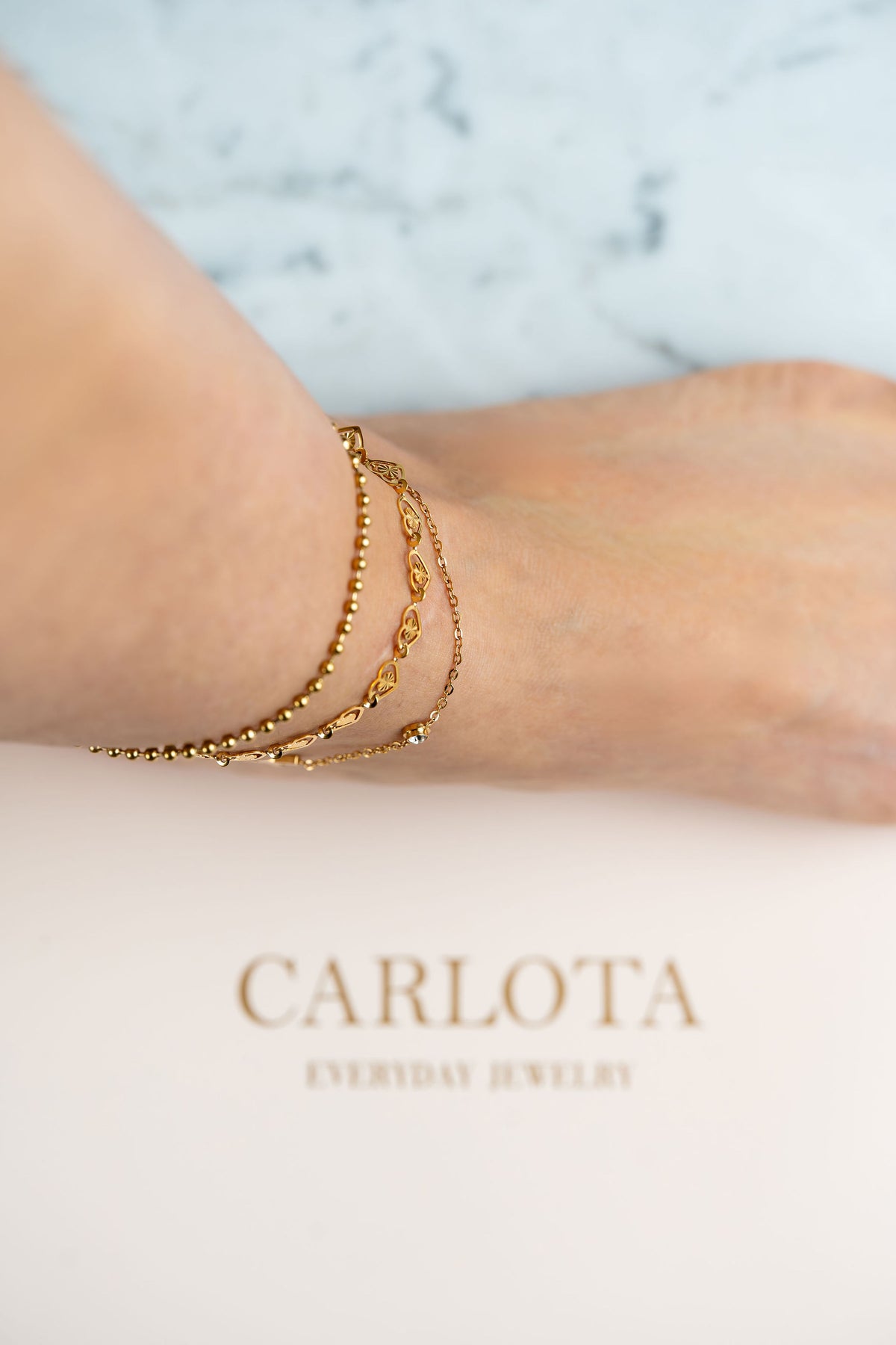 Tobilleras doradas  en acero quirúrgico en pie.