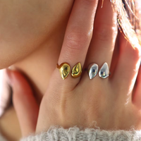 Anillos en acero quirúrgico color plata y dorado con diseño de doble gota ajustable, en modelo.

