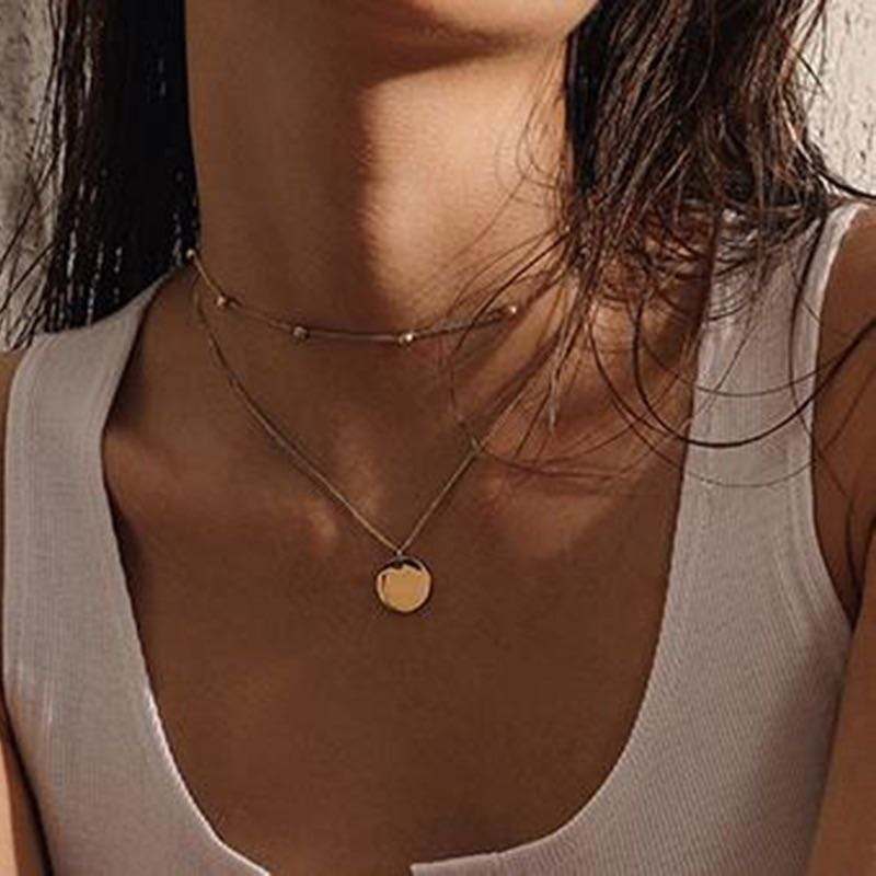 Collar doble de acero quirúrgico y baño de oro 18k con dijes redondos, diseño elegante y moderno en modelo