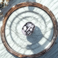 Anillo ancho dorado con acabado facetado brillante sobre bandeja de marmol

