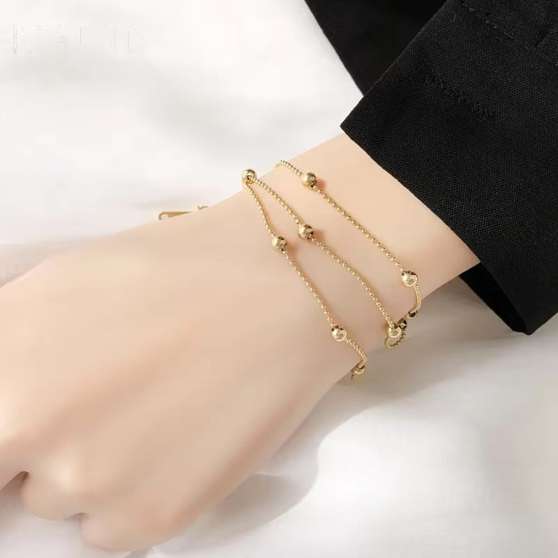 Pulsera triple en acero dorado con cuentas en mano