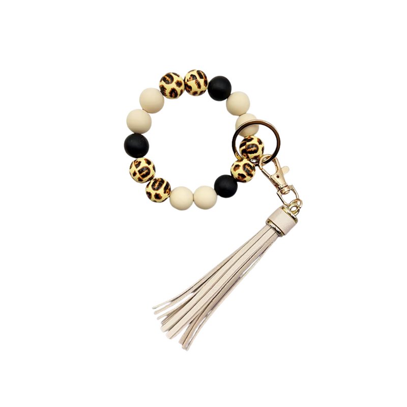 Llavero tipo pulsera con cuentas animal print, cuentas nude y negras, y colgante de flecos en tonos beige.