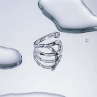 Anillo Praia de acero quirúrgico con diseño abierto y forma curva orgánica.
