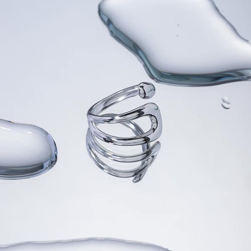 Anillo Praia de acero quirúrgico con diseño abierto y forma curva orgánica.
